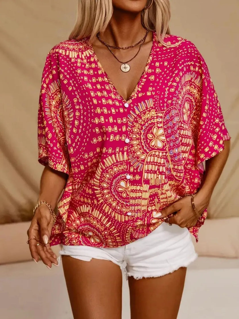 V-neck pink printed blouse with gold patterns, loose fit, button front, cotton blend texture.