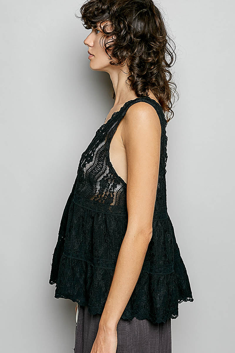 Black lace sleeveless top with deep V-neck and scalloped ruffled hem detail on woman