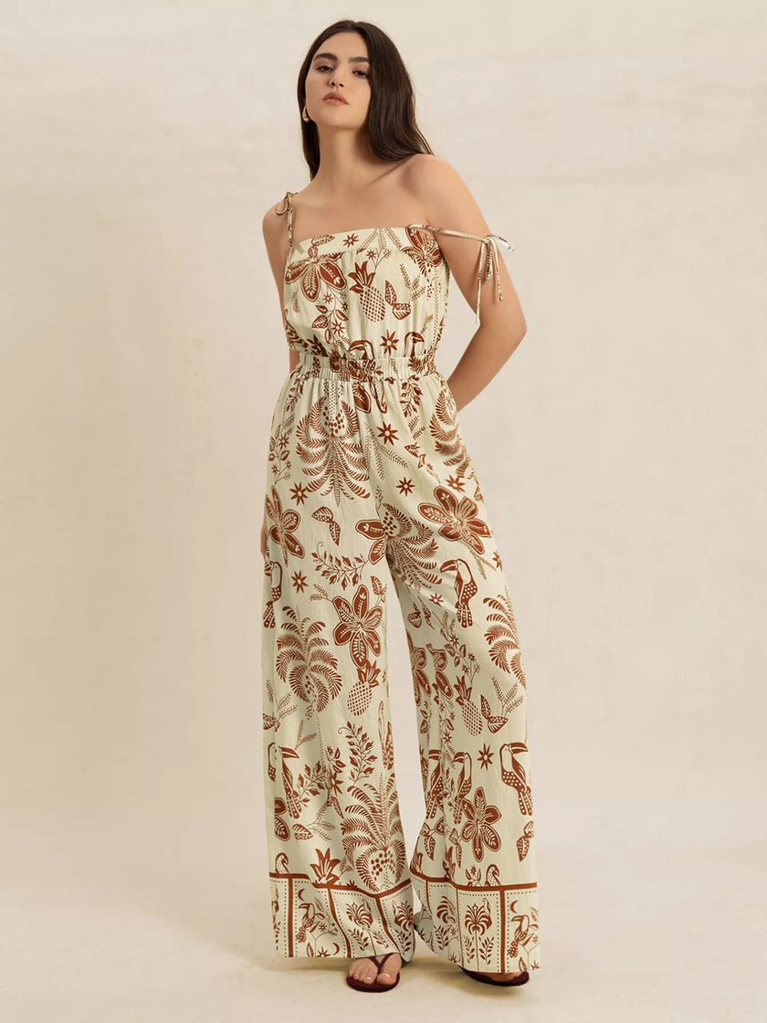 Cream base jumpsuit with brown tropical print, wide legs, tie straps, smocked waist.