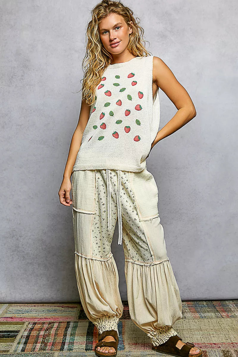 Cream knit sweater top with red strawberry pattern and green leaves, sleeveless round neck design.