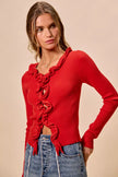 Red ribbed knit cardigan with cascading ruffles, fitted silhouette, denim pairing
