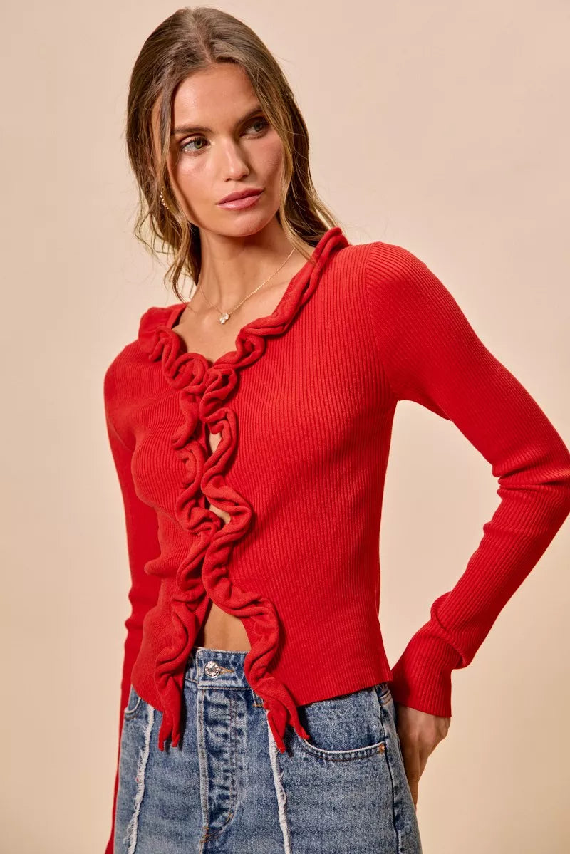 Red ribbed knit cardigan with cascading ruffles, fitted silhouette, denim pairing