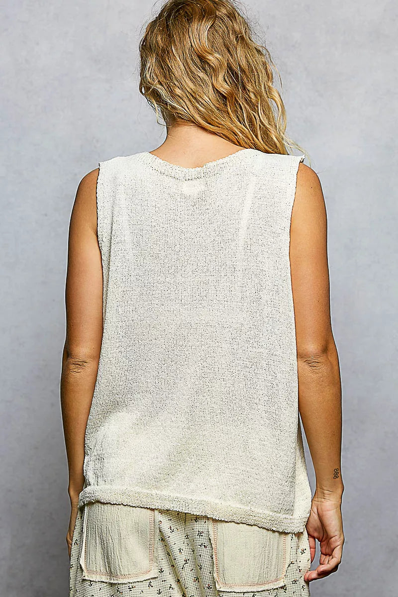 Cream knitted sleeveless top with textured knit and round neckline worn by woman