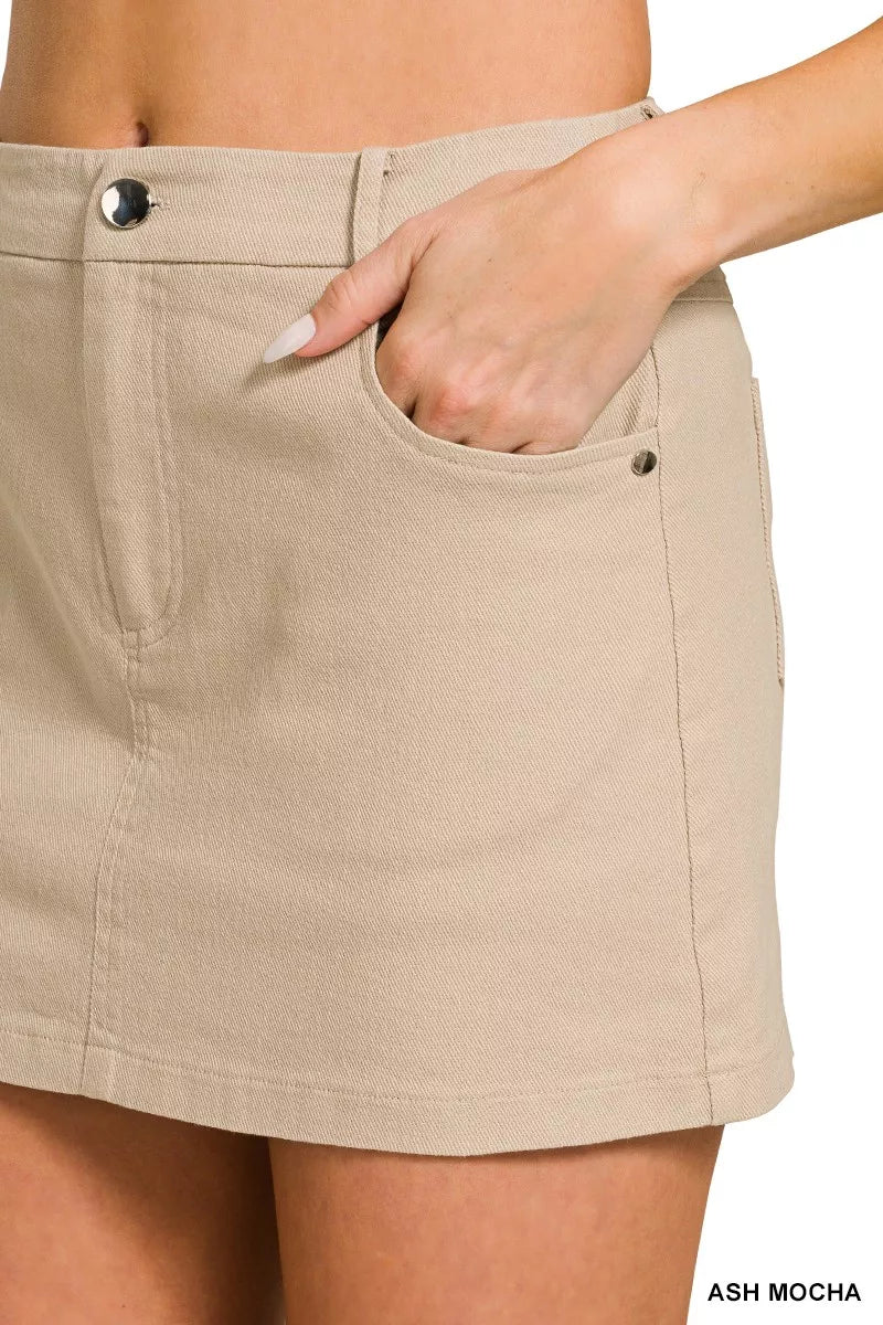 Beige cotton twill mini skirt with side pockets, button closure, and slim fit