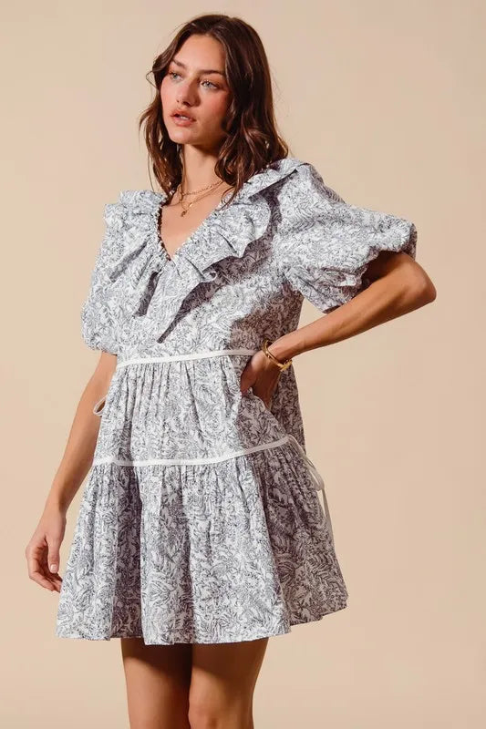 Gray and white cotton dress with ruffled V-neck, puff sleeves, and tiered skirt with side tie