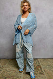Light blue openwork cardigan with scalloped edge, loose fit, crochet texture, paired with distressed jeans.