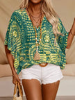 Green and yellow patterned V-neck top with loose fit and wooden bead necklace accent.
