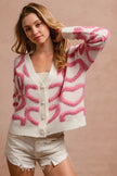 Pink and white textured heart pattern buttoned V neck cardigan with frayed denim shorts.