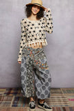 Cream crochet cardigan with black floral pattern, tassel hem, cropped fit, straw hat.