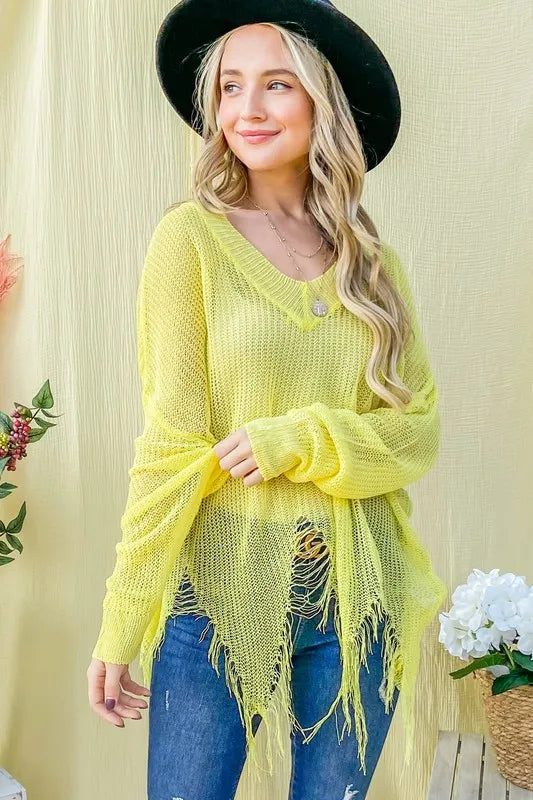 Yellow distressed mesh v-neck sweater with frayed hem and long sleeves worn over jeans