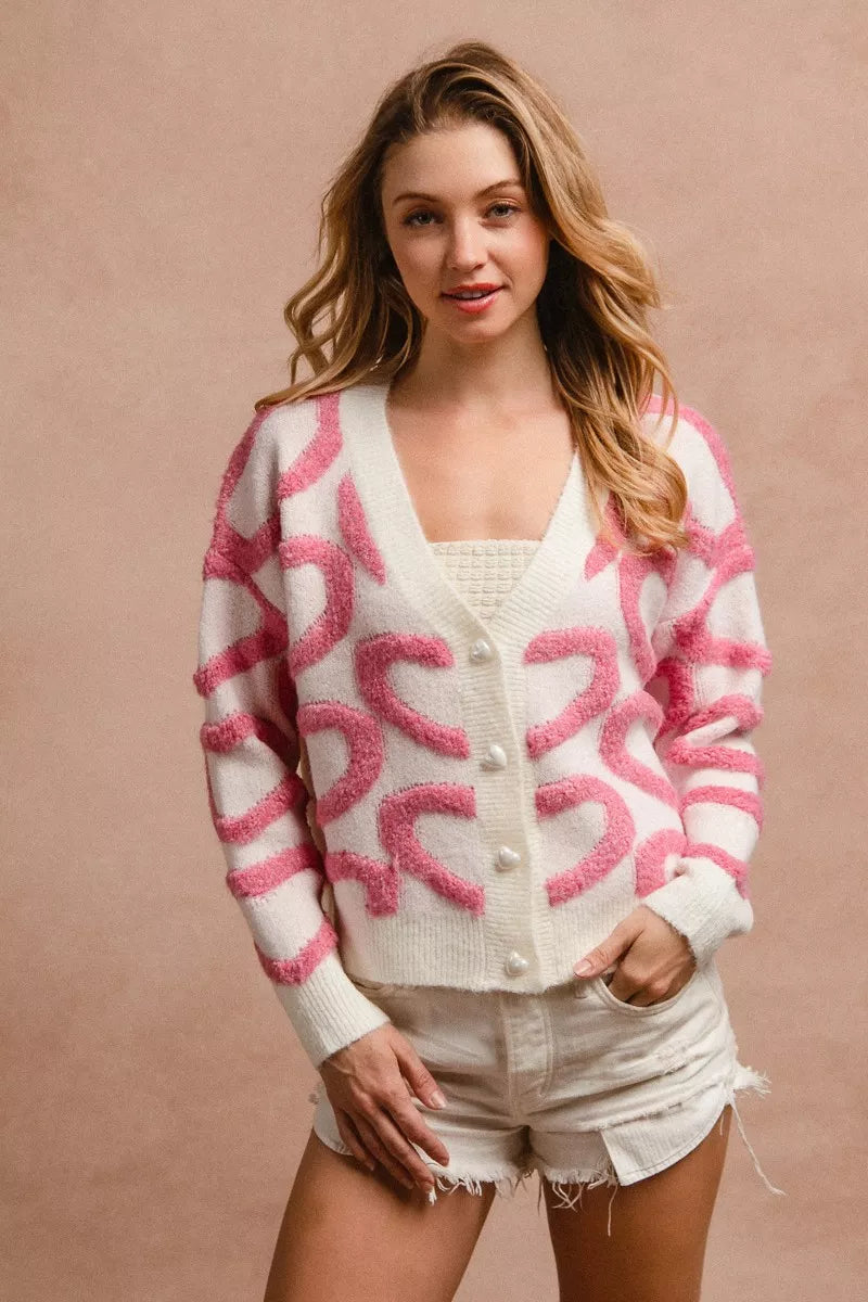 Pink and cream textured heart patterned buttoned V neck cardigan with cozy knit fabric and relaxed fit.