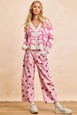 Pink textured heart patterned cardigan with buttoned V-neck and cropped fit.