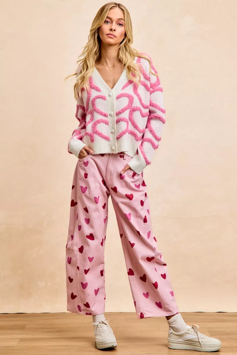 Pink textured heart patterned cardigan with buttoned V-neck and cropped fit.