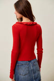 Red ribbed sweater with ruffled neckline and slim fit denim pairing
