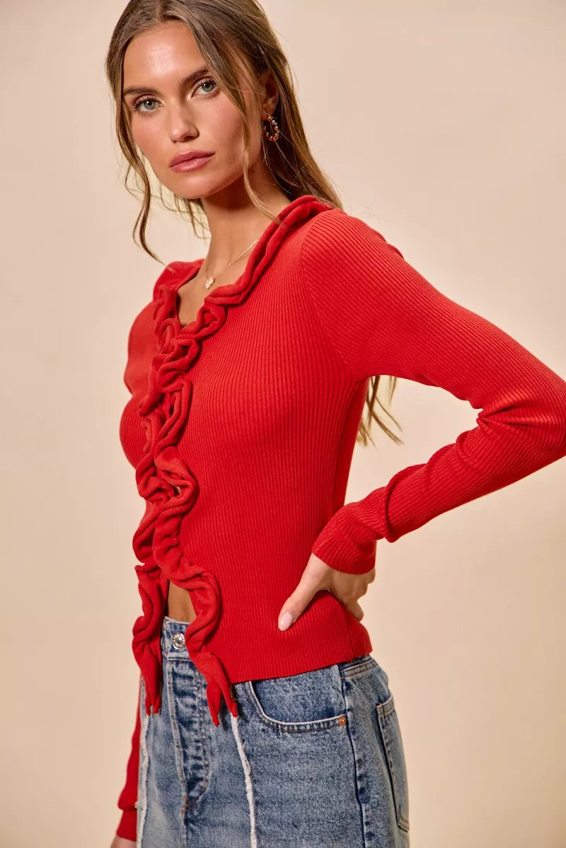 Red ribbed sweater with cascading ruffles, fitted long sleeves, denim pairing