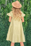Pale yellow cotton gauze babydoll dress with ruffled tiered skirt and short sleeves worn with a wide-brim hat
