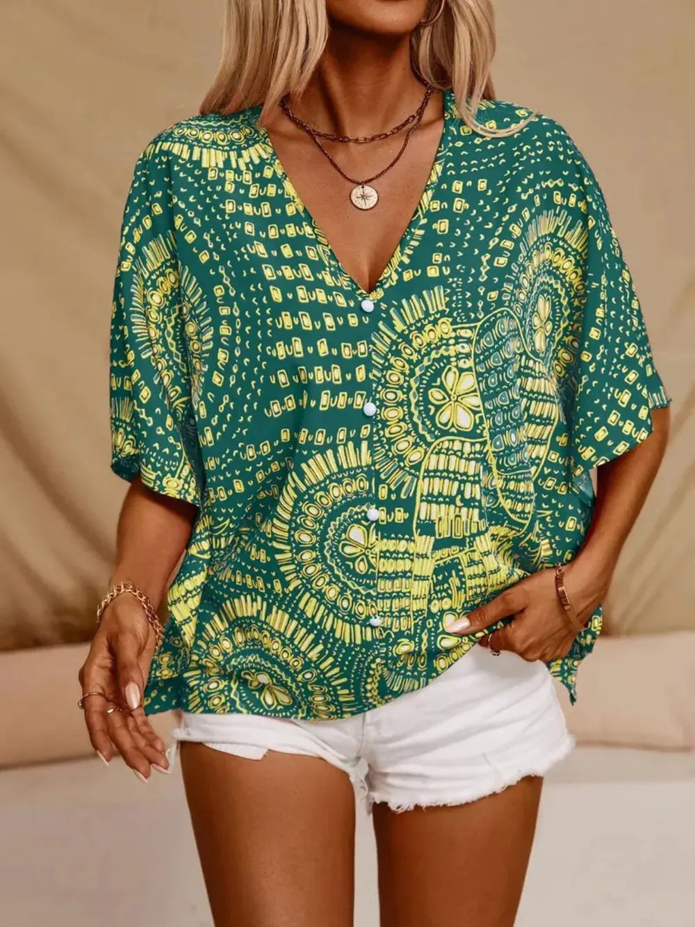 Green and yellow patterned V-neck blouse with button front and loose fit.