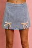 Light wash denim mini skirt with a flared fit and cream lace ribbon bows