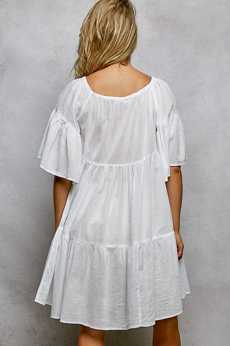 Back view of white textured mini dress with tiered skirt and flared short sleeves