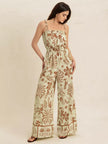 Light green tropical print wide leg jumpsuit with tie straps and smocked waist