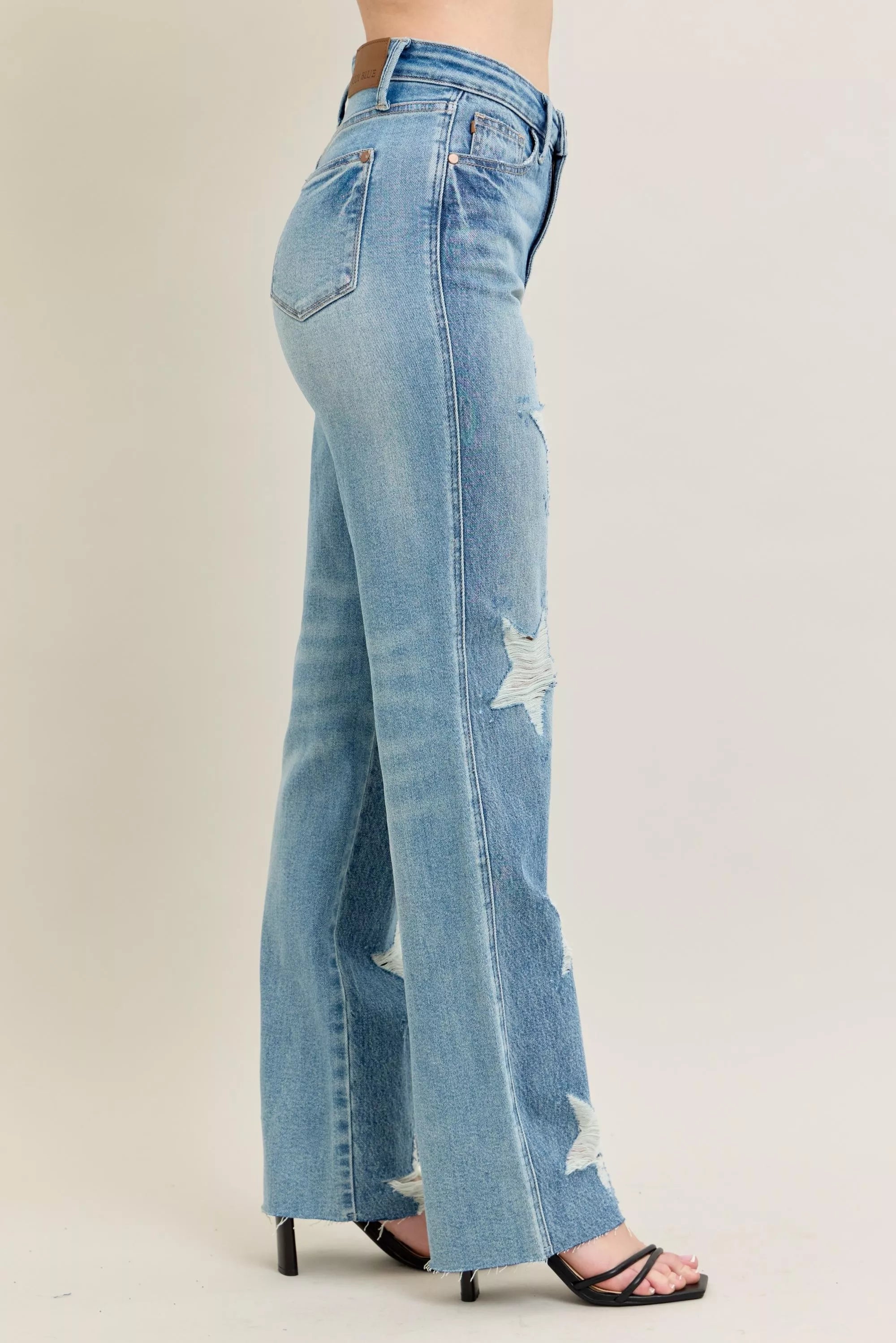 High-waisted 90s-style rigid distressed denim jeans, plus size, with faded blue washes and intentional frayed details.