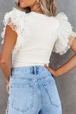 White ribbed blouse with ruffled cap sleeves, fitted waist, polka dot overlay