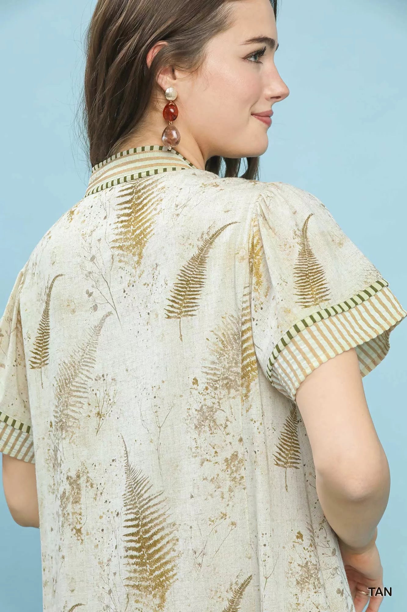Tan linen dress with gold fern print, striped trim, and side pockets