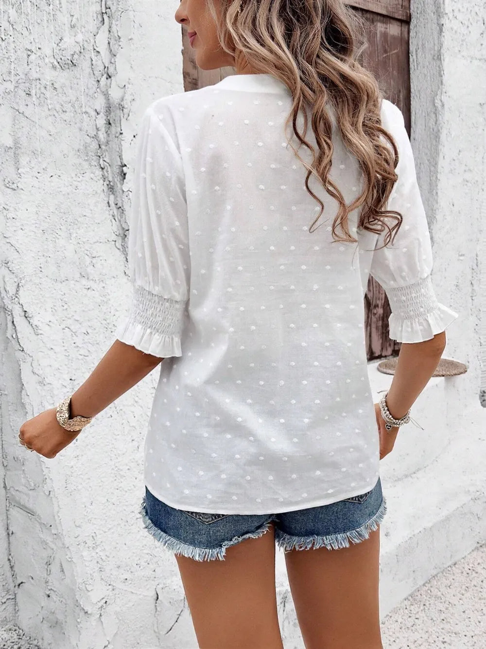 white blouse with flounce sleeves hanging on a rack