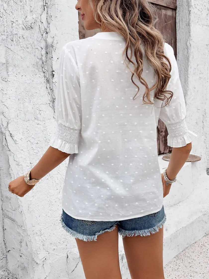 white blouse with flounce sleeves hanging on a rack