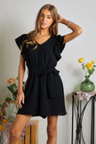 Black romper showcasing front pocket design and ruffle trim