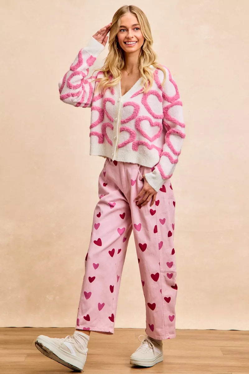 Pink textured heart patterned V-neck cardigan with button closure and cropped fit.