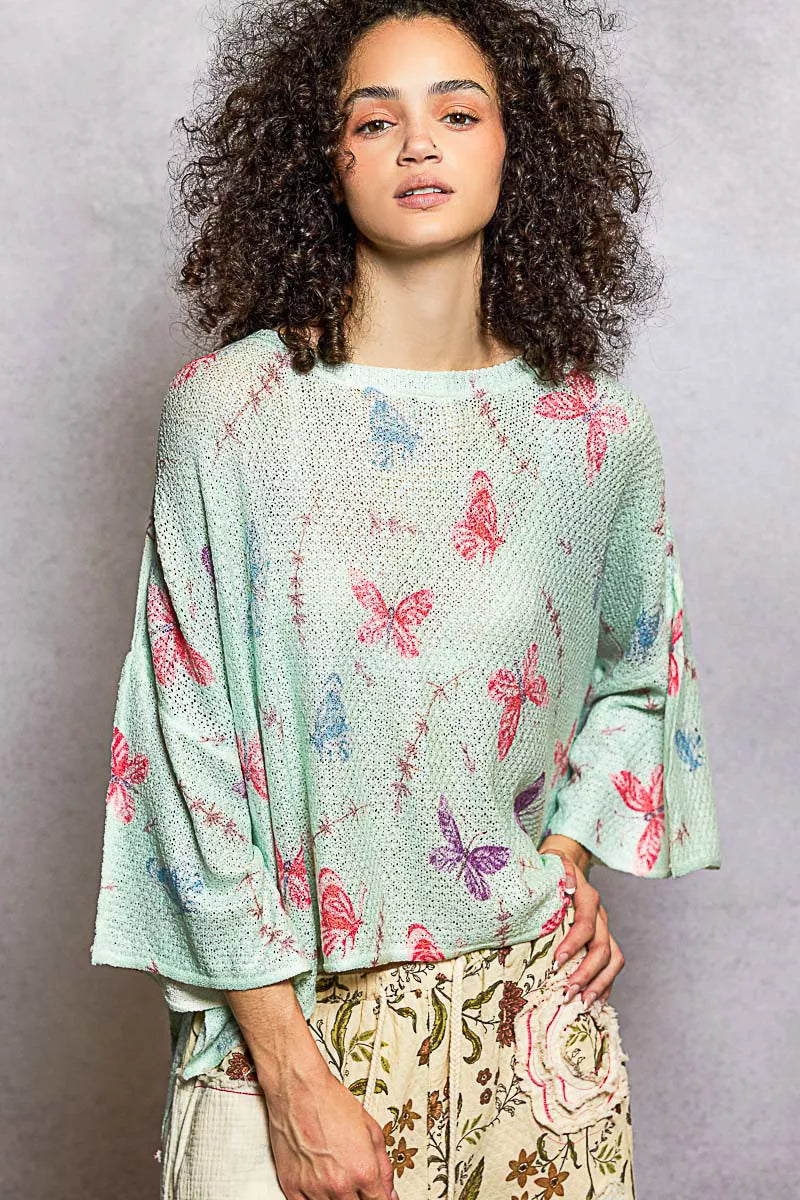 Close-up of mint green butterfly print on relaxed knit top