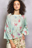 Close-up of mint green butterfly print on relaxed knit top