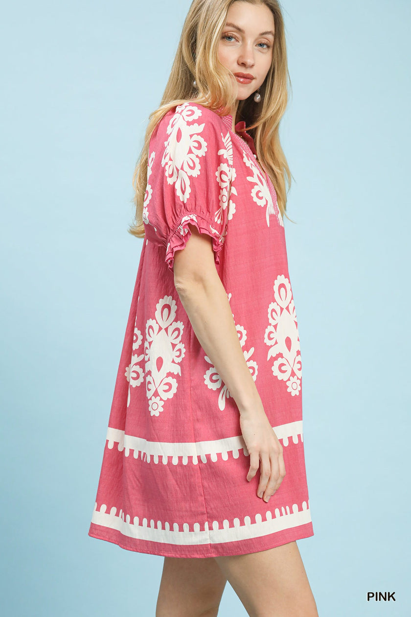 A-line pink linen mini dress with white floral print, ruffle sleeves, and scalloped border hem.