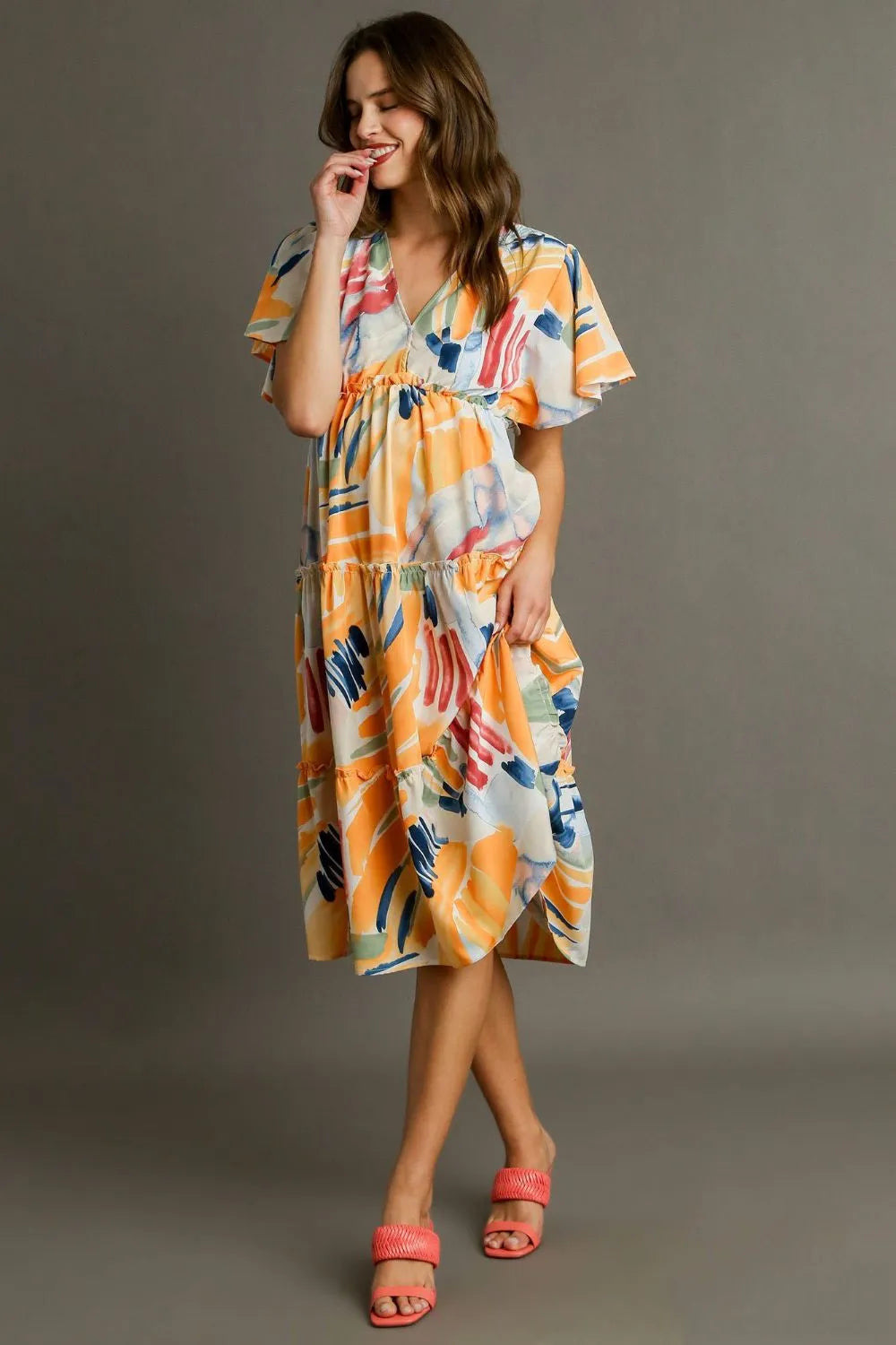 Orange blue abstract print flutter sleeve tiered midi dress with frill waist and flowing fabric.
