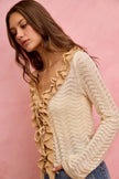 Cream and beige pointelle knit cardigan with ruffled side ties and fitted silhouette.