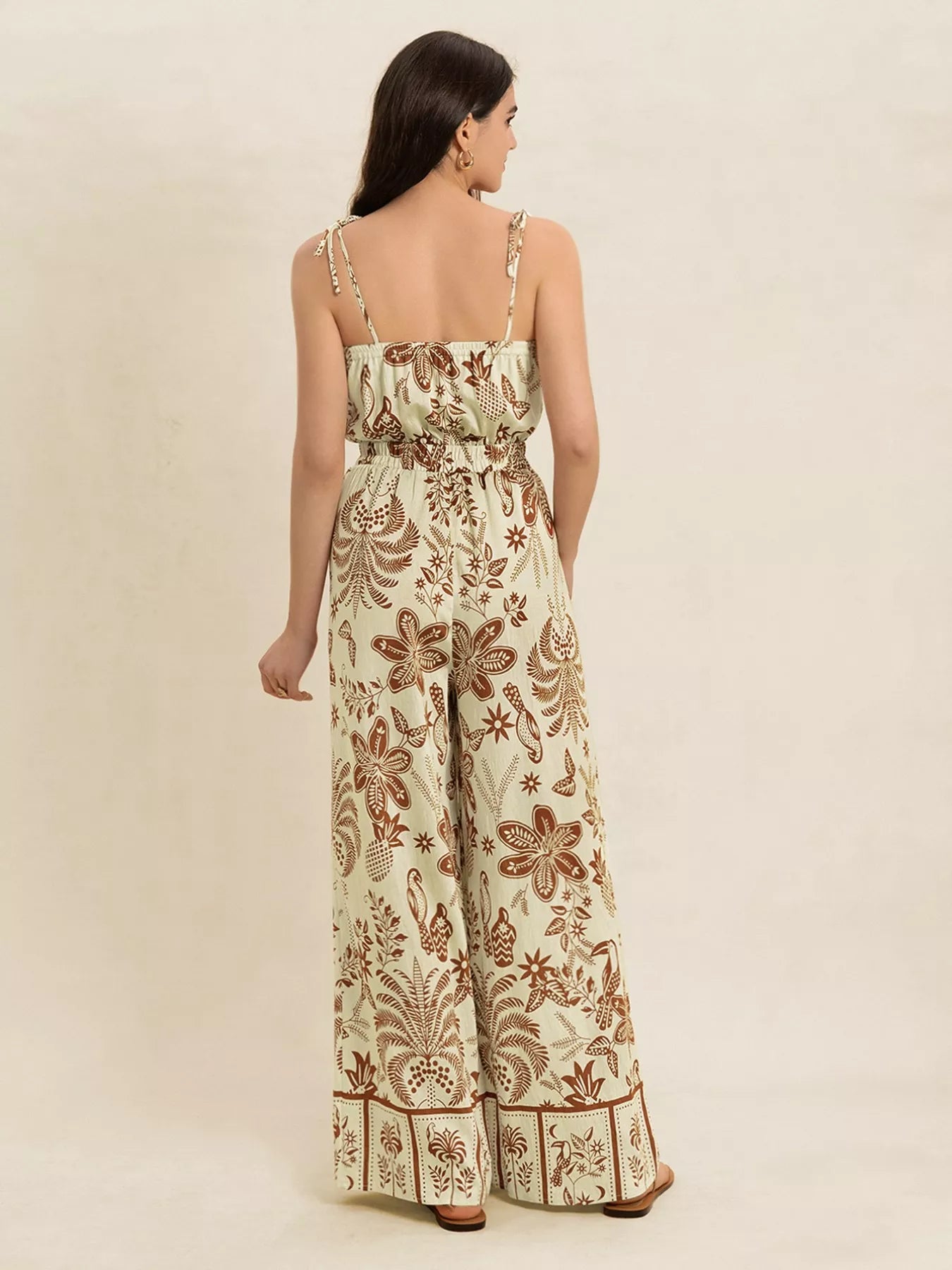Cream base with brown tropical print, smocked waist, wide leg, tie straps jumpsuit