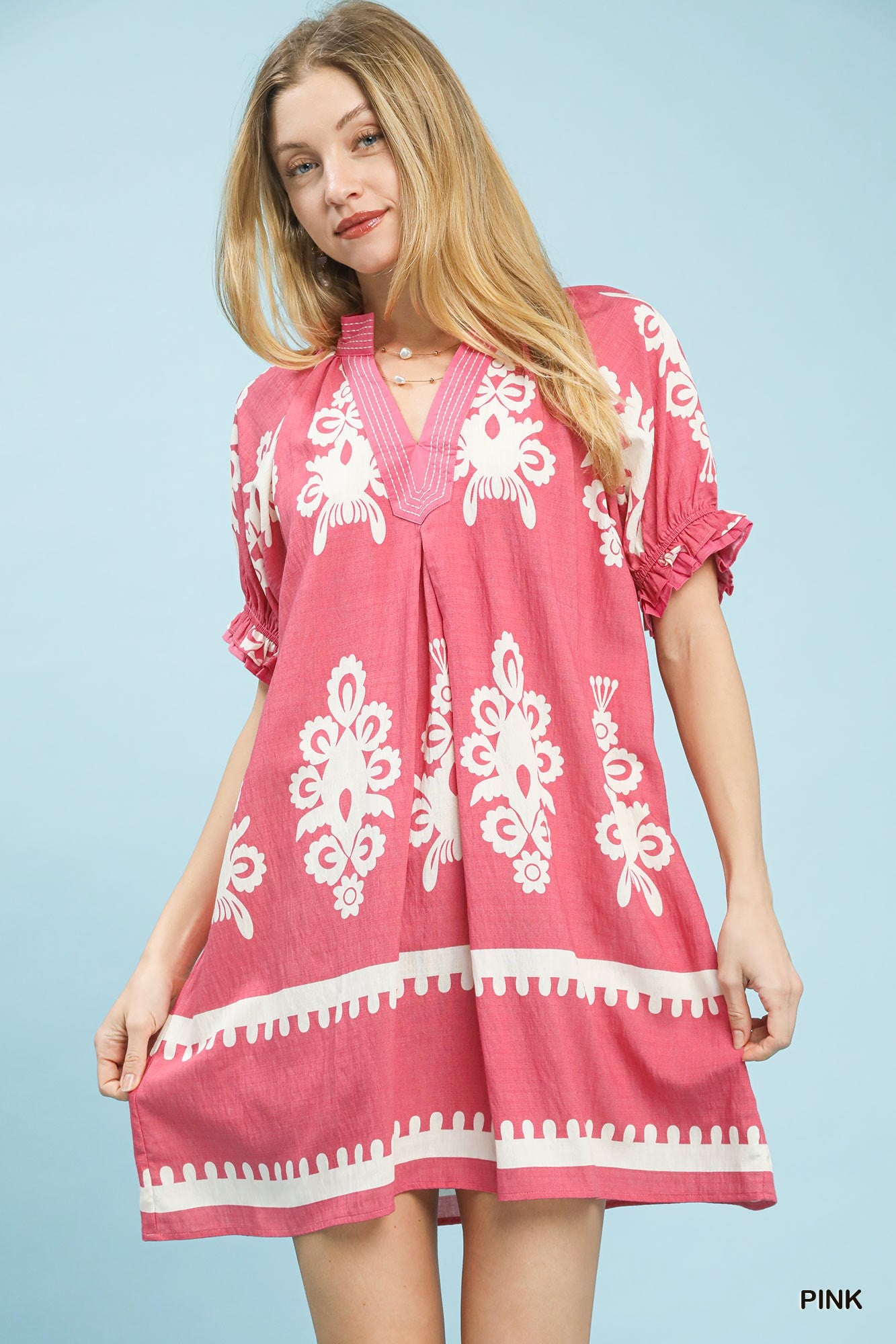 Pink mini dress with white border and floral print, ruffled sleeves, and loose linen fit.
