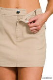 Beige cotton twill mini skirt with button waist, textured fabric, and side pockets