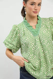 Green-and-white leaf print blouse featuring puff sleeves and ruffled neck