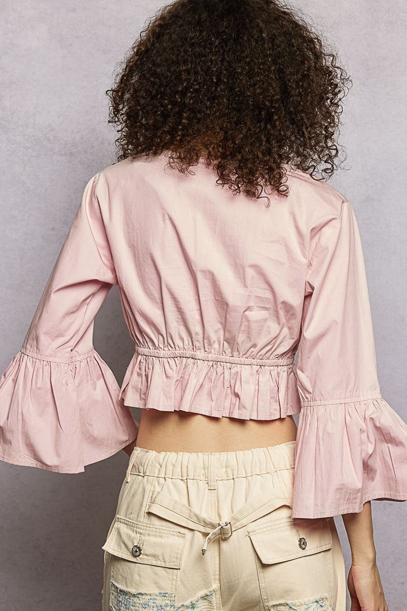 Back view of light pink cropped blouse with flared sleeves and elasticated ruffled hem
